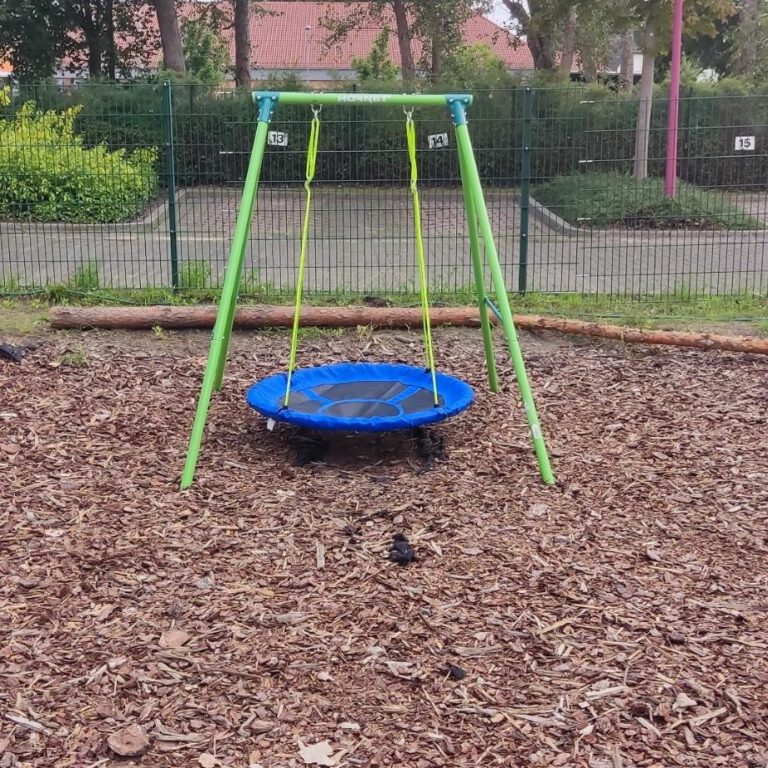 Nestschaukel mit grünem Gestell auf einem Spielplatz mit Rindenmulch in Hellersdorf